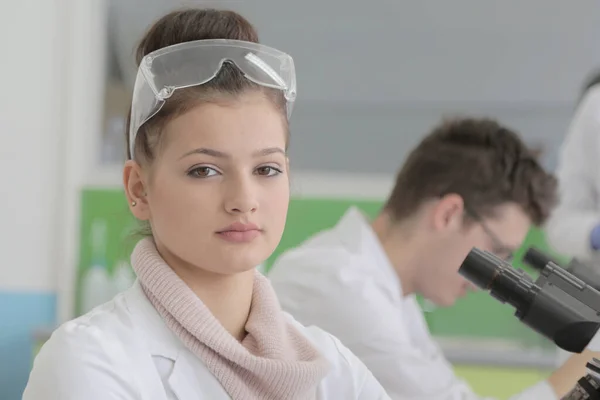 Deux jeunes scientifiques de laboratoire des deux sexes travaillent en laboratoire avec des éprouvettes et un microscope — Photo