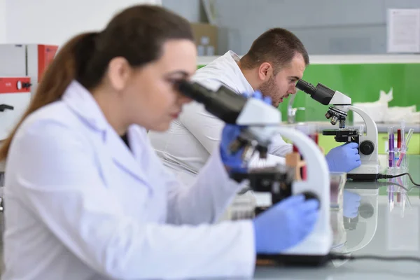Dos jóvenes mujeres y hombres científicos de laboratorio que trabajan en el laboratorio w — Foto de Stock