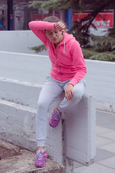 Young female runner prepairing for jogging in the city street. Fit body requires hard work. Urban sport concept. Young female exercising in sport clothes.