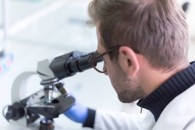 Laboratuvarda test tüpleri, mikroskop, test veya araştırma ile çalışan genç erkek laboratuvar bilim adamı. Bilim, kimya, biyoloji, tıp ve insan konsepti..