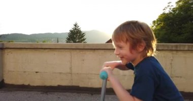 Şehir sokağında scooter 'ı olan komik çocuk. Pozitif duygu ve ifade. Scooter süren gülümseyen çocuk. Sağlıklı çocukluk