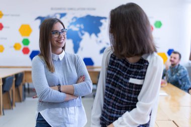 İki çalışkan öğrenci kız güneşli kütüphanede sohbet ediyorlar..