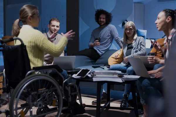 Handicapped young woman with colleagues working in office. She is smiling and passionate about the workflow. Performing in co-working space. Office people working together.