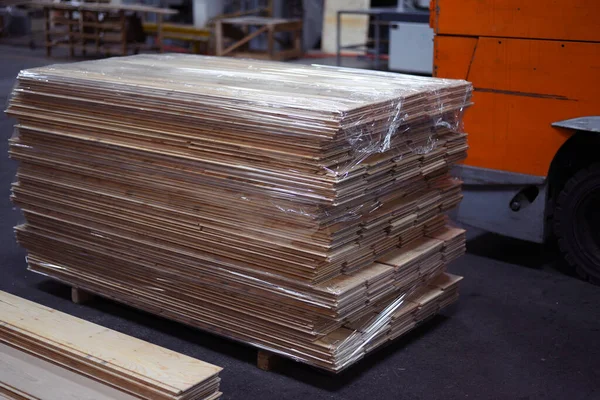 Timber Flooring Factory. Pile of cut wood in factory storage warehouse. Lumber in warehouse.