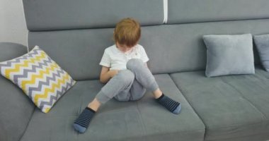 Küçük çocuk evde kalmak ya da oynamak için telefonu kullanıyor. Kafkasyalı çocuk evde oyun oynayarak ya da telefonda öğrenerek zaman geçiriyor. Küçük çocuğun karantina yüzünden evde kalması gerekiyor.