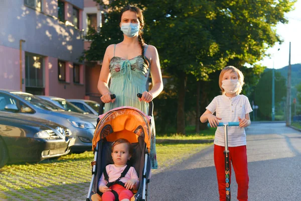Kids with mother walking on the street with face masks for COVID-19. Self isolation and social distancing.