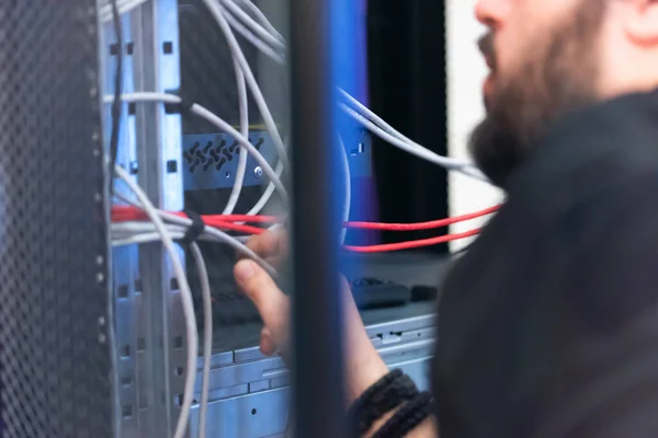 An Expert Engeneer in datacenter server room  connecting cables in server cabinet in network server room.