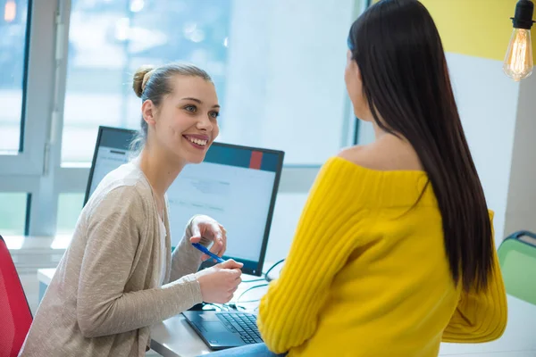 Two young women working together with computer at the office. Businesswomen start work with new project, good brainstorm results, victory concept.