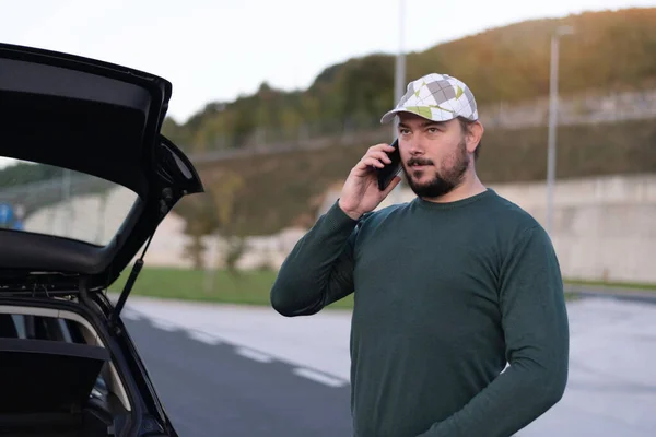 Man calling road assistance on the highway. Calling car service, assistance or  tow truck while having troubles with his car.