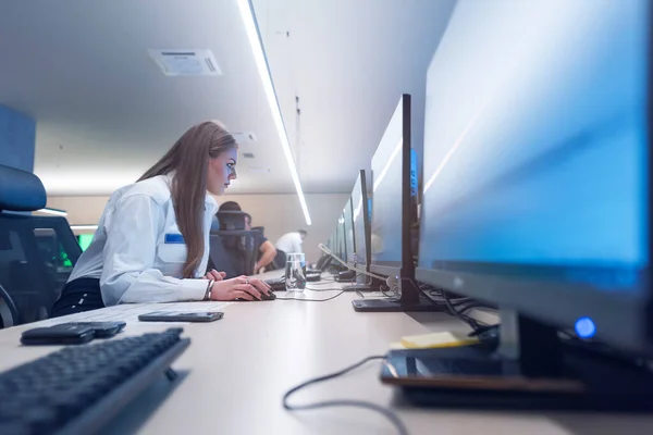 Female security guards working in surveillance room, monitoring cctv and discussing.