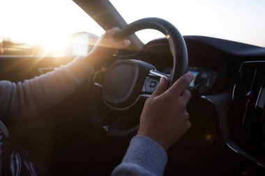 Başarı devrede. Gün batımında otoyolda araba süren yakışıklı genç adam..