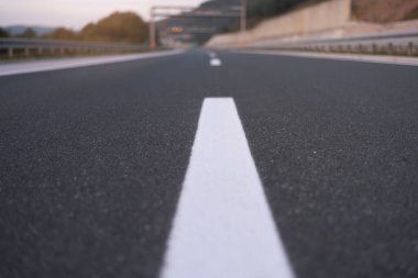 Gün batımında yeşil tarlalarda ve dağlarda boş otoyol.