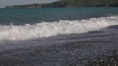 Boş bir çakıl taşı plajına deniz dalgaları çarpıyor.