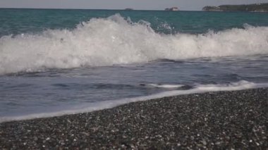 Boş bir çakıl taşı plajına deniz dalgaları çarpıyor.