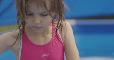 Küçük kız bahçedeki şişme yüzme havuzunda oynuyor. 