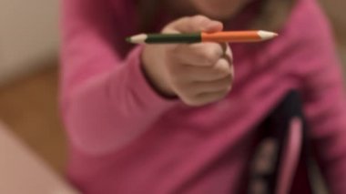 Okul masasında aydınlanmış bir küreyle resim çizen ve tablet izleyen sevimli küçük kız, seçici bir odak noktası.