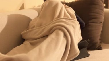 Oturma odasındaki kanepede uzanmış tableti izleyen güzel küçük kız.