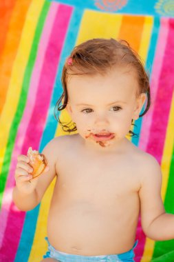 Kumsalda çörek yiyen bir bebek, tarlanın sığ derinliğine dikkat edin.