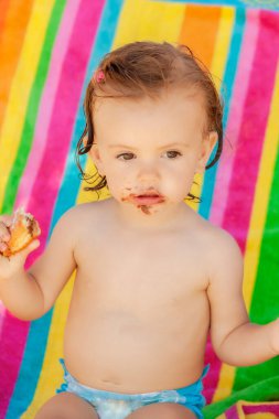Kumsalda çörek yiyen bir bebek, tarlanın sığ derinliğine dikkat edin.
