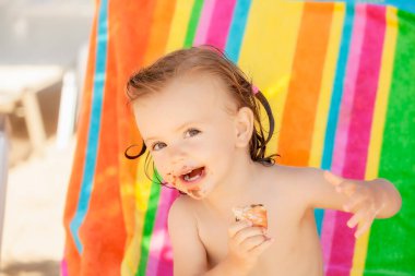 Kumsalda çörek yiyen bir bebek, tarlanın sığ derinliğine dikkat edin.