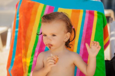 Kumsalda çörek yiyen bir bebek, tarlanın sığ derinliğine dikkat edin.