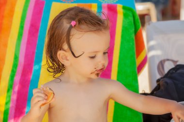 Kumsalda çörek yiyen bir bebek, tarlanın sığ derinliğine dikkat edin.