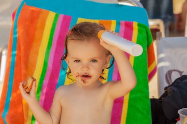 Kumsalda çörek yiyen bir bebek, tarlanın sığ derinliğine dikkat edin.