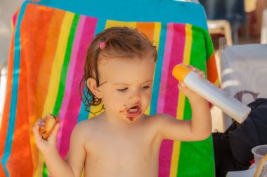 Kumsalda çörek yiyen bir bebek, tarlanın sığ derinliğine dikkat edin.
