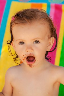 Bebek, kumsalda çikolatalı çörek yiyor. Sahada sığ bir derinlik var.
