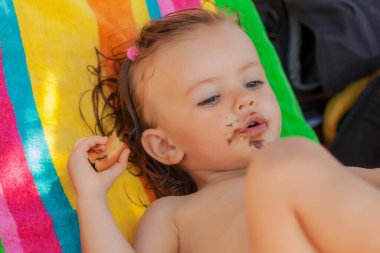 Kumsalda çörek yiyen bir bebek, tarlanın sığ derinliğine dikkat edin.