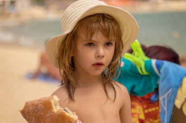 Kumsalda çörek yiyen bir kız.