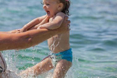 Bir çocuk denizde yüzmeyi öğrenir, yüzeysel alan derinliğine dikkat edin.