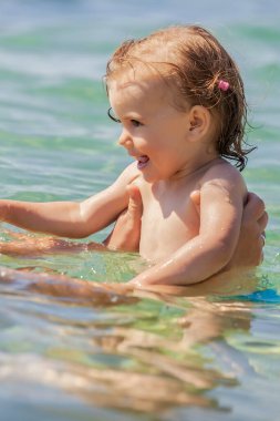 Bir çocuk denizde yüzmeyi öğrenir, yüzeysel alan derinliğine dikkat edin.