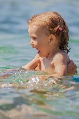 Bir çocuk denizde yüzmeyi öğrenir, yüzeysel alan derinliğine dikkat edin.