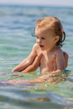 Bir çocuk denizde yüzmeyi öğrenir, yüzeysel alan derinliğine dikkat edin.