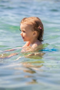 Bir çocuk denizde yüzmeyi öğrenir, yüzeysel alan derinliğine dikkat edin.