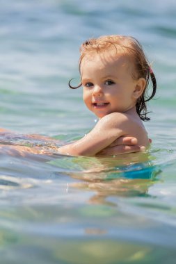 Bir çocuk denizde yüzmeyi öğrenir, yüzeysel alan derinliğine dikkat edin.