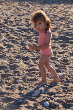 Küçük kız kumlu bir sahilde yürüyor, derin bir tarlada.