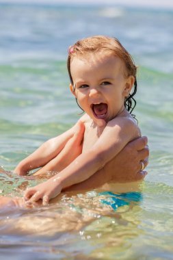 Bir çocuk denizde yüzmeyi öğrenir, yüzeysel alan derinliğine dikkat edin.