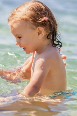 Bir çocuk denizde yüzmeyi öğrenir, yüzeysel alan derinliğine dikkat edin.