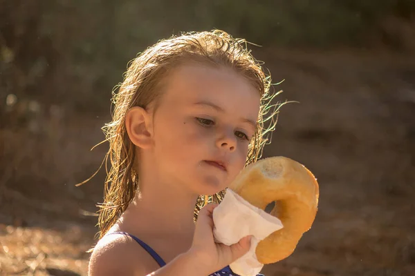 Klein Meisje Eten Een Donut Het Strand — Stockfoto