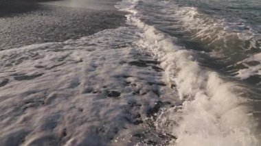 Yukarıdan çekilen boş bir sahile çarpan dalgaların yakın çekimi, yavaş çekim.