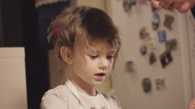 Sevimli küçük kız annesiyle mutfak masasında bisküvi yapıyor.