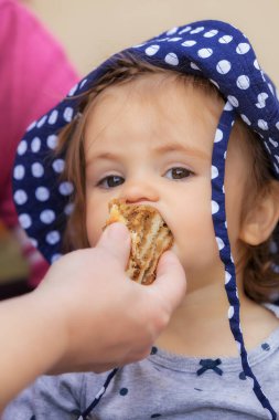 Çocuk kafasında nokta olan bir şapkayla bisküvi yiyor, alanın derinliğine dikkat edin.