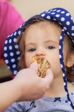 Çocuk kafasında nokta olan bir şapkayla bisküvi yiyor, alanın derinliğine dikkat edin.