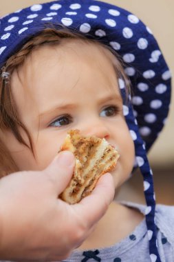 Çocuk kafasında nokta olan bir şapkayla bisküvi yiyor, alanın derinliğine dikkat edin.