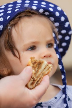 Çocuk kafasında nokta olan bir şapkayla bisküvi yiyor, alanın derinliğine dikkat edin.