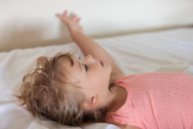 Çocuk büyük bir yatakta yatıyor, derin bir alan derinliğine dikkat edin.