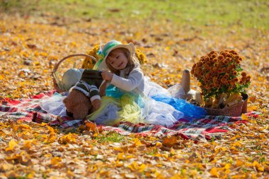 Sonbahar güneşinde şapkalı küçük kız Bea 'siyle oynuyor.