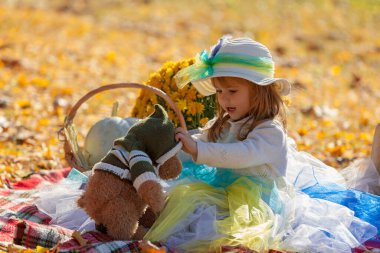 Sonbahar güneşinde şapkalı küçük kız Bea 'siyle oynuyor.